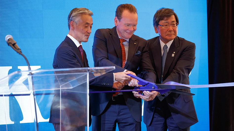 Three men in suits hold a large pair of purple scissors and cut a purple ribbon strung in front of them.