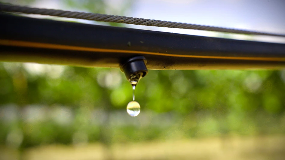 A drop of water falls from a black pipe.